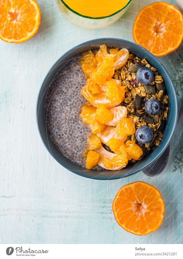 Chia pudding with tangerines and granola chia pudding bowl pastel turquoise matcha tea wooden background blueberry breakfast chia seeds dessert food plant based