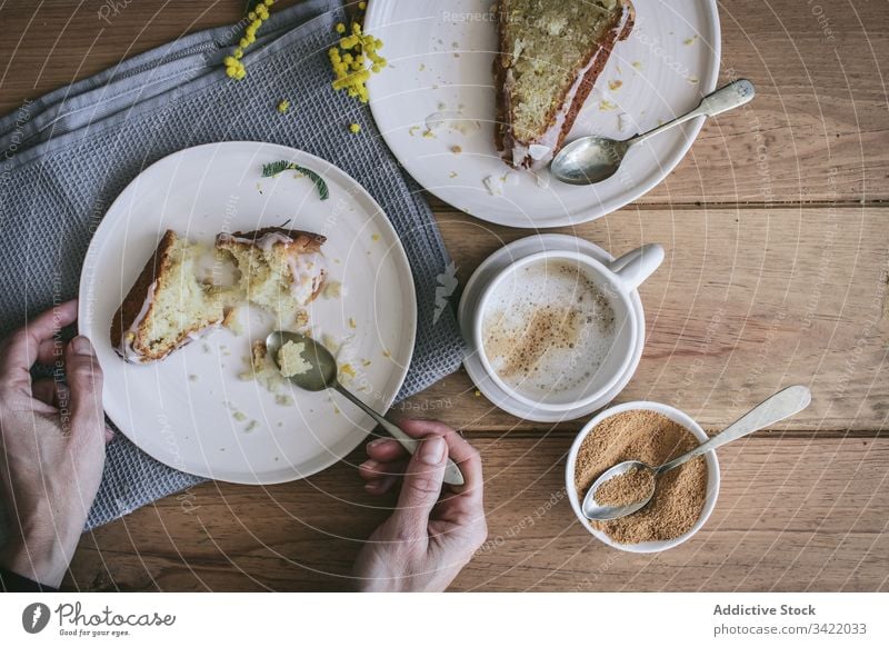 Anonymous woman having breakfast with delicious fresh pie cake dessert lemon coconut slice piece cup coffee table plate hand arm wooden ingredient serve