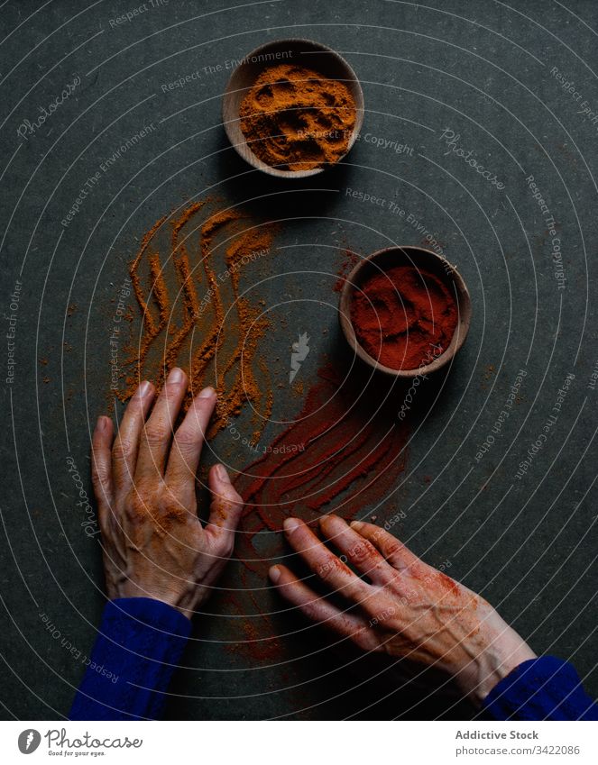 Spilled powdered spices on male hands paprika cinnamon pepper spill natural aromatic condiment seasoning culinary food chili ground bowl pot person creative