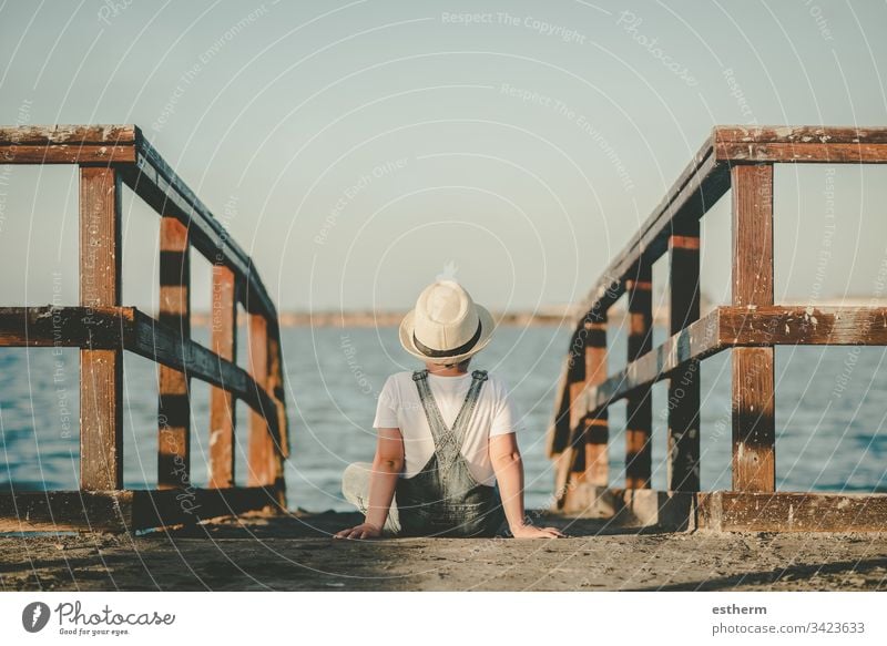 Back view of a Pensive child sitting looking at the sea childhood nostalgic thoughtful Thought loneliness lonely expression freedom innocence portrait serious