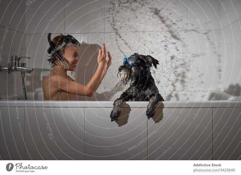 Happy boy with his dog in the bathtub bathroom showering water childhood home little clean caucasian kid lifestyle hygiene happiness smiling adorable soap cute