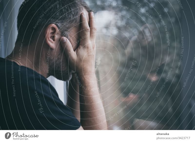 portrait one sad man standing near a window sadness loss problem depressed serious fear grief frustration anxiety unhappy person adult despair shame upset