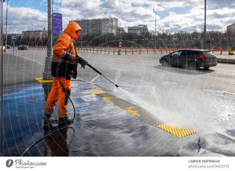 Road worker cleaning city street with high pressure power washer, cleaning dirty public transport stops, Moscow, Russia industrial water equipment man service