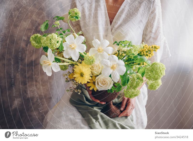 Young woman in a white dress holding vase with flowers. Vintage, romantic concept. bouquet girl metal sit sitting chair soft light beautiful vintage wedding