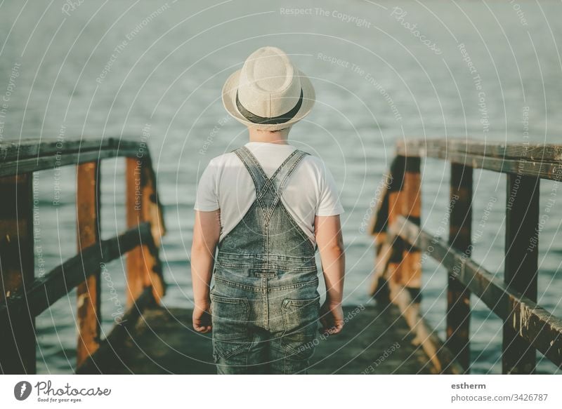 Back view of a Pensive child looking at the sea childhood nostalgic thoughtful Thought loneliness lonely expression freedom innocence portrait serious dream