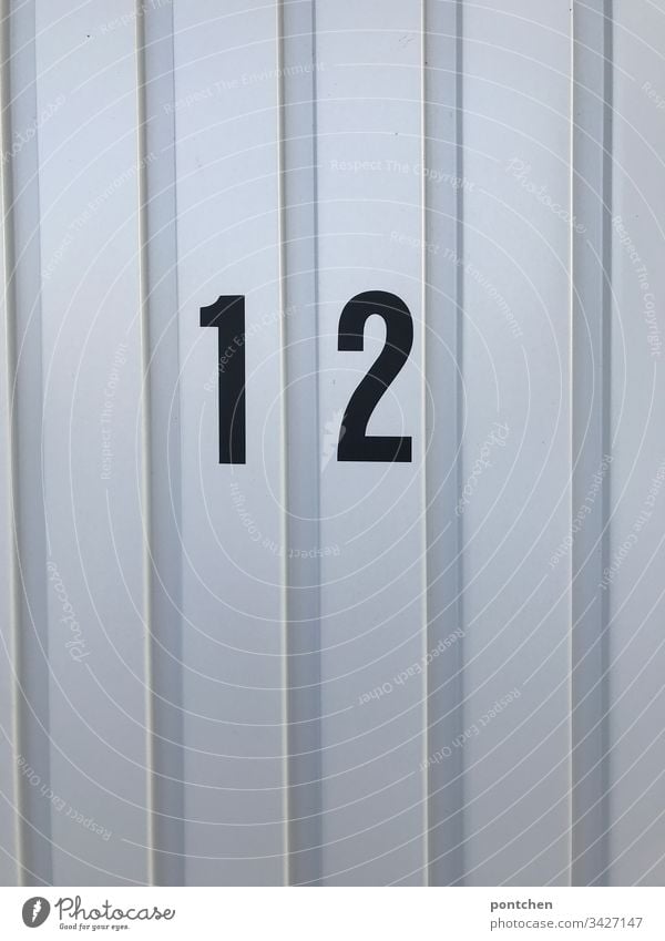 Black number twelve 12 on garage door Garage Goal Corrugated sheet iron Garage door Exterior shot Deserted Colour photo Monochrome Copy Space bottom Day