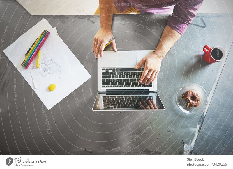 Top view of architect man working at computer in office laptop business breakfast workplace hands keyboard desk table technology notebook coffee up writing