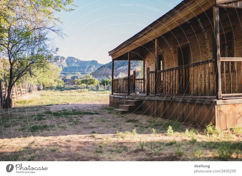 Wooden veranda of a brick house in the evening light Calm straightforwardness Ghost town Sun Deep depth of field Loneliness Old Brown Back-light Tracks