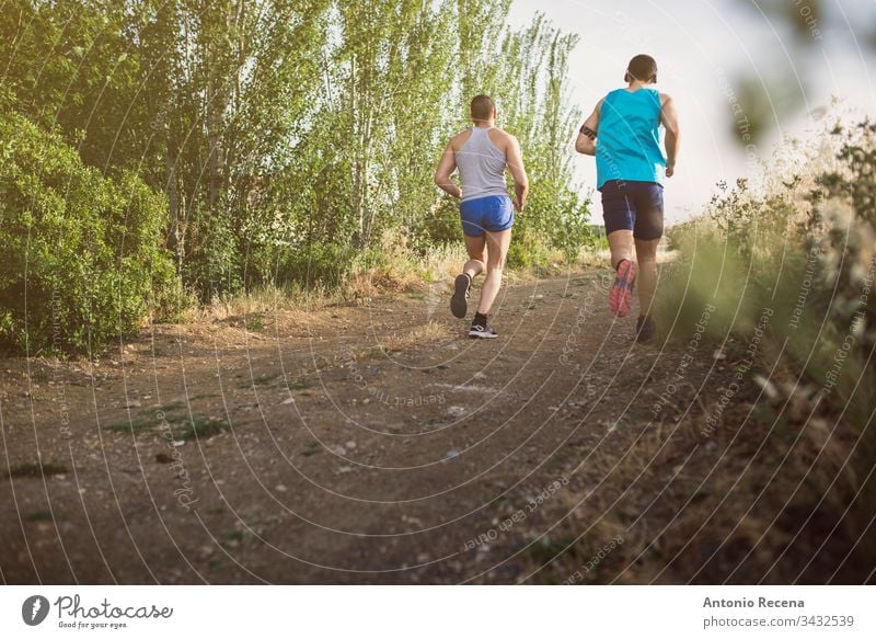 Two runners running outdoors men man jog jogging sportsperson together lifestyles two male adult road people active back rear view full length walking