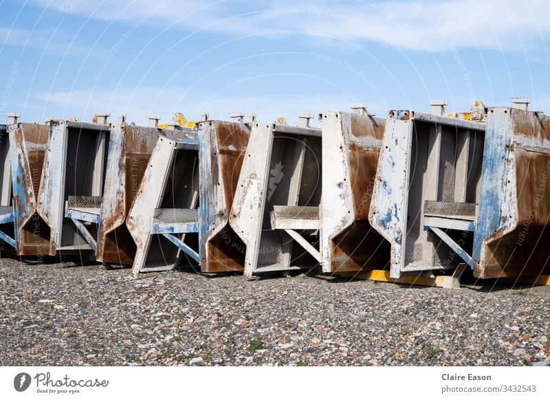 Heavy non specific factory production equipment, lined up outside on a gravel surface with a blue sky. factory equipment factory machinery Factory yard