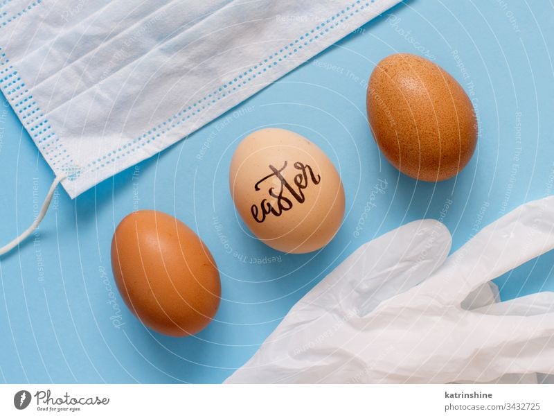 Gloves, facemask and eggs with inscription EASTER over blue background gloves top view coronavirus concept latex light blue flat lay above celebration covid-19