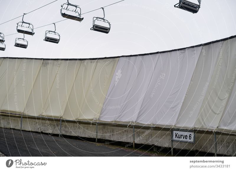 Chairlifts without people unpeopled grey sky covered bobsleigh track muted grey and beige tones