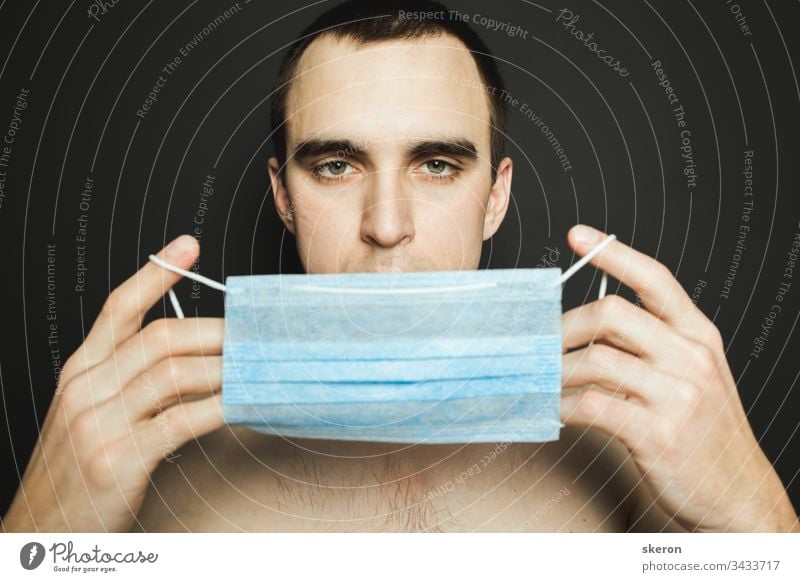 Portrait of a man with medical facial mask who is concerned about preventing pandemic coronavirus on a gray background. quarantine and pandemic concept. Man wearing aseptic mask to prevent illness.