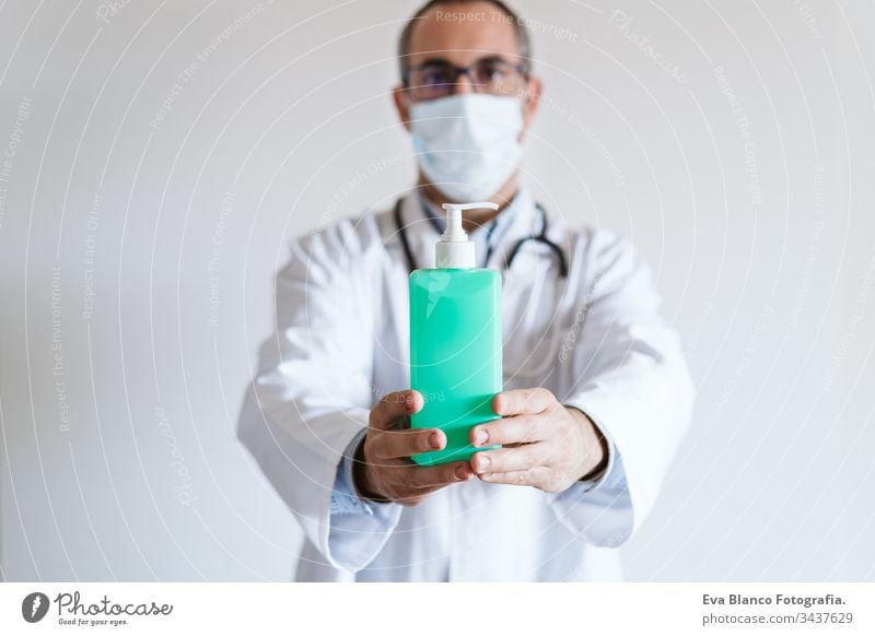 doctor man wearing protective mask indoors. Holding an alcohol gel or antibacterial disinfectant. Hygiene and corona virus concept. Covid-19 professional