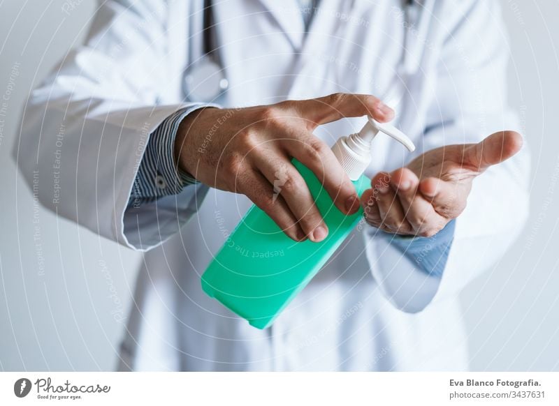 doctor man wearing protective mask indoors. Holding an alcohol gel or antibacterial disinfectant. Hygiene and corona virus concept. Covid-19 professional