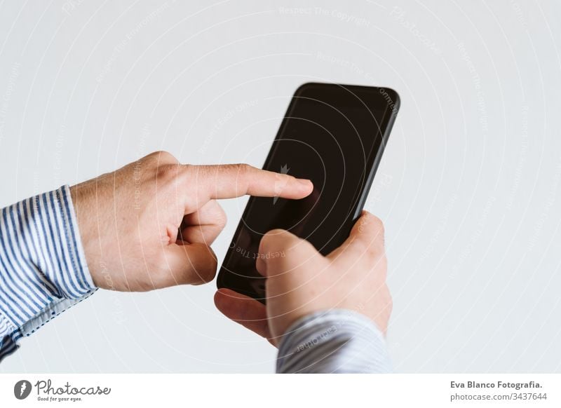 close up view of a man using mobile phone indoors. Technology concept unrecognizable technology wireless shirt working internet texting finger executive