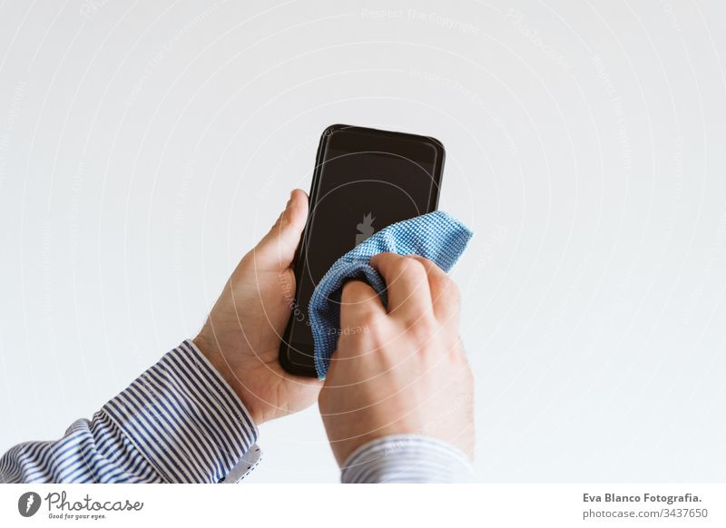 close up view of a man cleaning mobile phone with disinfectant. Hygiene and coronavirus covid-19 concept corona virus hygiene screen anti bacterial soap liquid