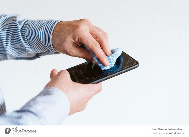 close up view of a man cleaning mobile phone with disinfectant. Hygiene and coronavirus covid-19 concept corona virus hygiene screen anti bacterial soap liquid