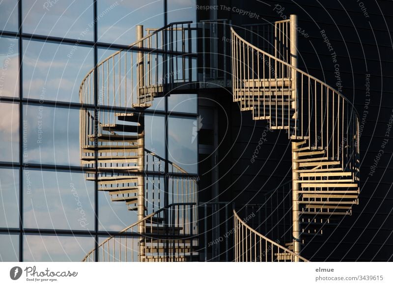 Spiral staircase in the evening sun and mirrored in a glass façade Stairs Winding staircase Evening sun Facade Glas facade Slice Architecture Deserted Building