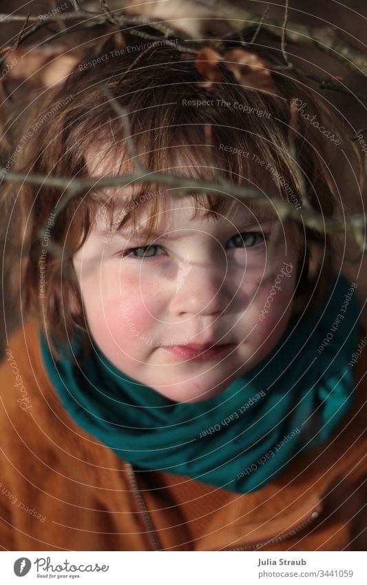 Girl looks sceptically upwards through branches Toddler girl fringe hairstyle red cheeks peel Branch Autumn Deciduous tree wollwalk mustard yellow turquoise