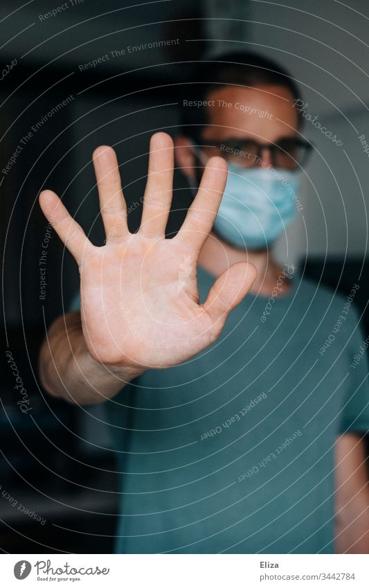 Man with face mask stretches out his arm to keep his distance during the Corona pandemic because he is contagious Mask corona Contagious Face mask