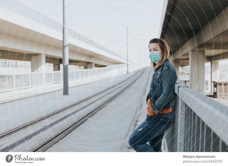 Young woman with a surgical mask in an empty tram station alone biohazard care caucasian city contagion coronavirus covid-19 covid19 danger disease epidemic