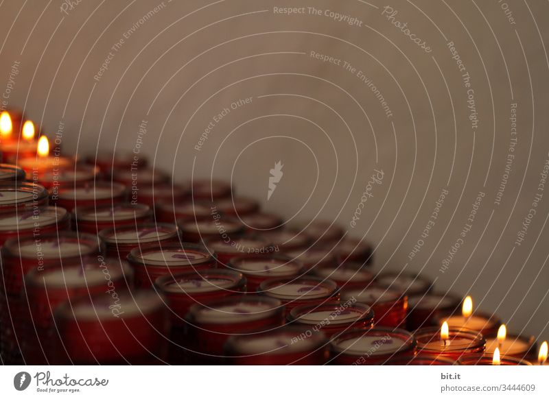 Burning, glowing candles in an offering box in the church, in front of a grey wall in a sad mood. Shallow depth of field Light (Natural Phenomenon) Reflection