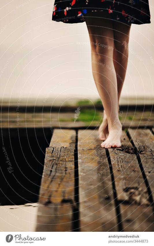 A girl walks on a wooden bridge to the lake. The bridge on the lake. Beautiful barefoot. alone summer legs lifestyle active background beach beautiful body