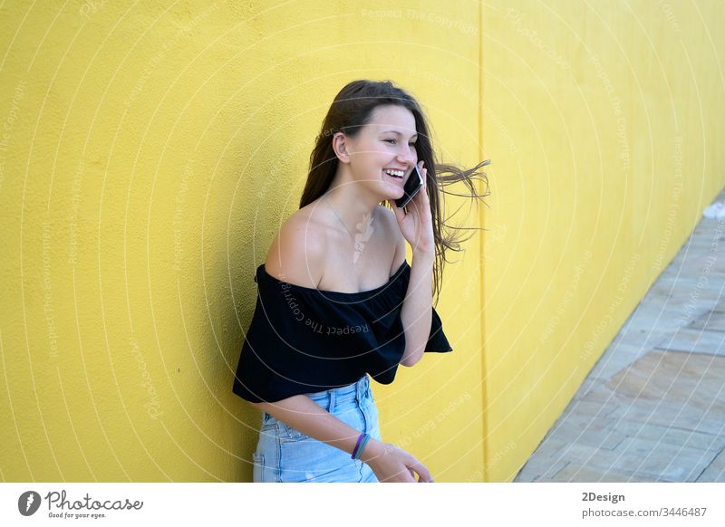 Beautiful girl leaning on yellow wall, young friendly woman smiling happy on a sunny day of summer 1 person female adult attractive background portrait smile