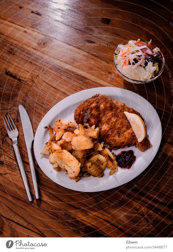 Wiener Schnitzel with fried potatoes viennese schnitzel Hash brown potatoes Bavaria Austria tribunal Down-to-earth Eating enjoyment Lettuce Meat breaded