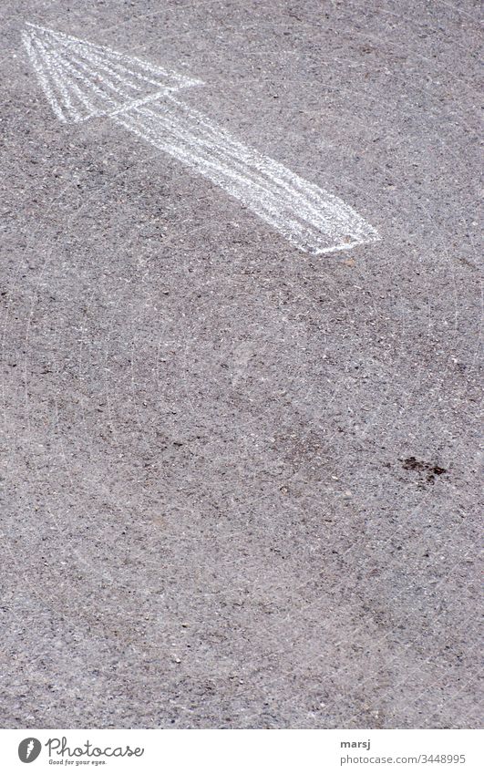 An arrow, drawn with chalk, on asphalt road, pointing to the upper left corner. Arrow groundbreaking Direction Asphalt Clue Subdued colour Contrast