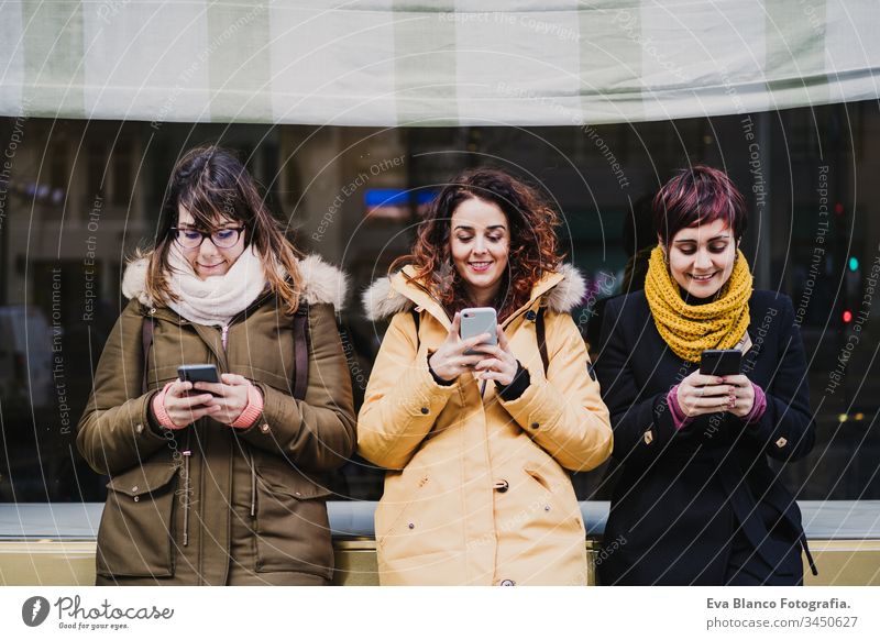 group of friends using mobile phone outdoors in the street. Happy women smiling. lifestyle and travel concept friendship tourist tourism three 3 technology city