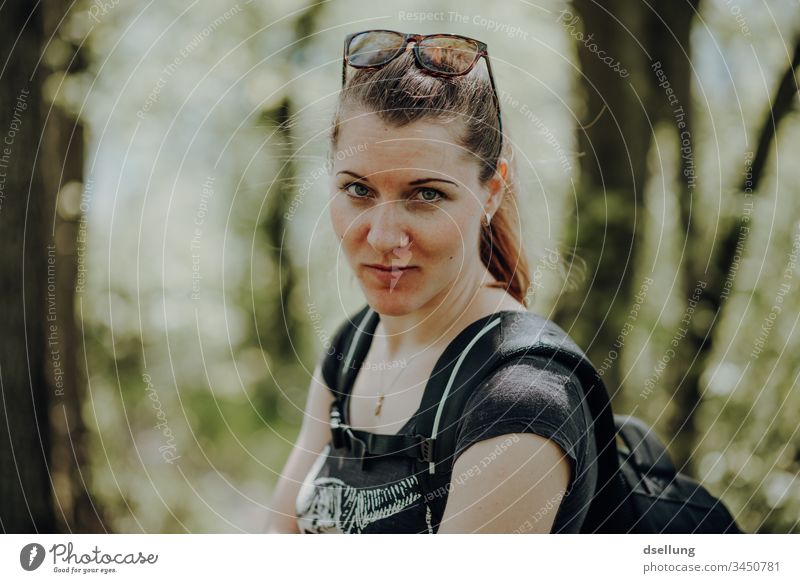 Young woman hiking in the forest with a view into the camera. So of course she does not go hiking with her gaze into the camera, but with her husband, who takes pictures of her looking into the camera.