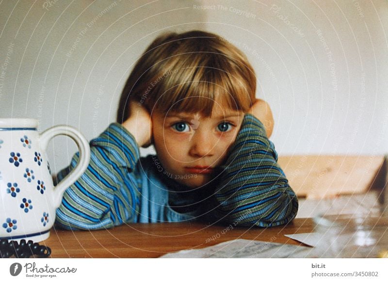 Little girl sits seriously at home at the table, supports her head in her hands and looks a little sad? Toddler Life Human being Infancy Child upbringing