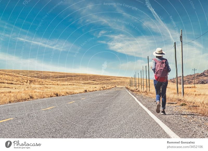 Beautiful woman hitchhiking on road in forest, hitchhiking with thumbs up in a countryside road, Travelling and hitchhiking concept. outdoors suitcase walking