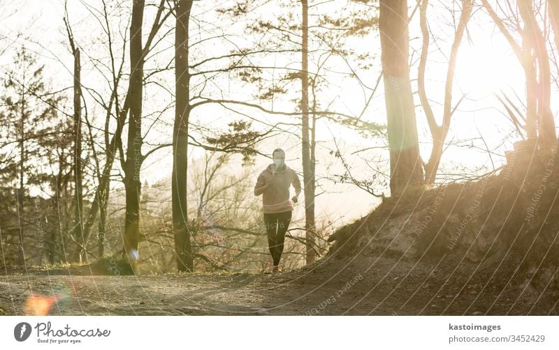 Corona virus, or Covid-19, is spreading all over the world. Portrait of caucasian sporty woman wearing a medical protection face mask while running in nature.