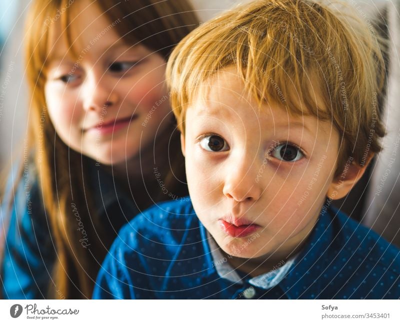 Two blonde cute kids in blue shirts child smile face family siblings brother sister redhead little funny sweet tender together near indoors portrait people