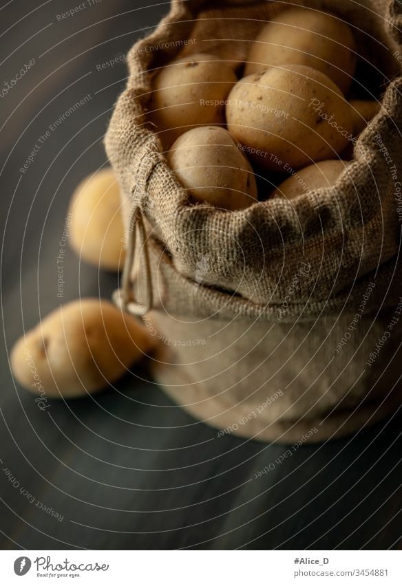 Potatoes in sackcloth on rustic wooden background bag brown burlap burlap sack close-up culinary diet earth earthy falling food fresh fresh potatoes group