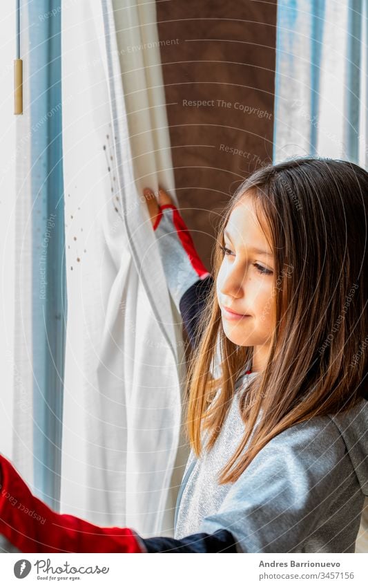 Portrait of pretty little girl with funny attitude looking out the window indoor child female kid young staring home glass friends rain children happiness