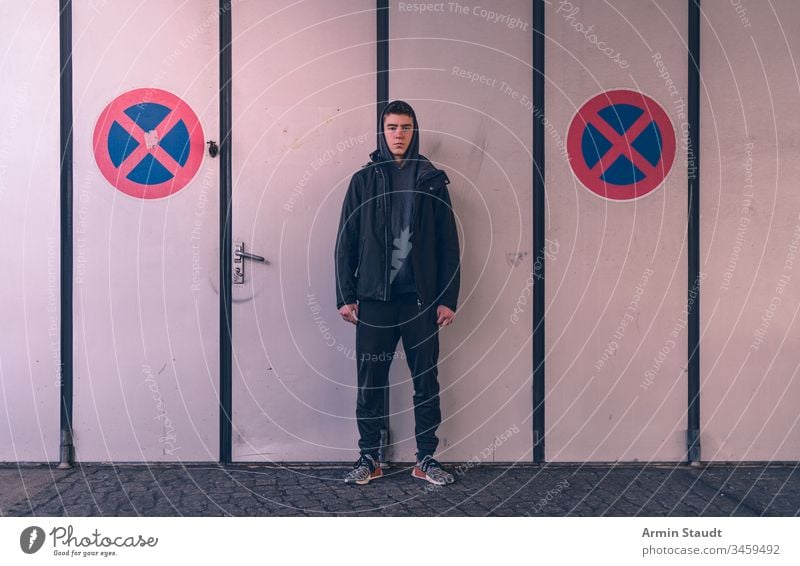 young man stands between two no parking traffic signs adolescent adult attractive beautiful beauty boy casual caucasian closeup confidence confident cool