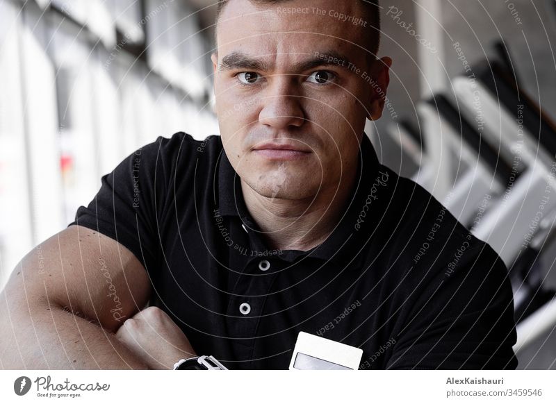 Portrait of young handsome fitness trainer man in gym while training around fitness equipment looking into the camera. Fitness Bodybuilder Man Sports Training