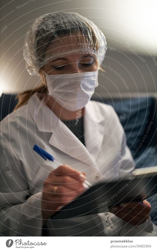 Doctor filling out a document. Hospital staff working at night duty. Woman wearing uniform, cap and face mask to prevent virus infection doctor flu sick care