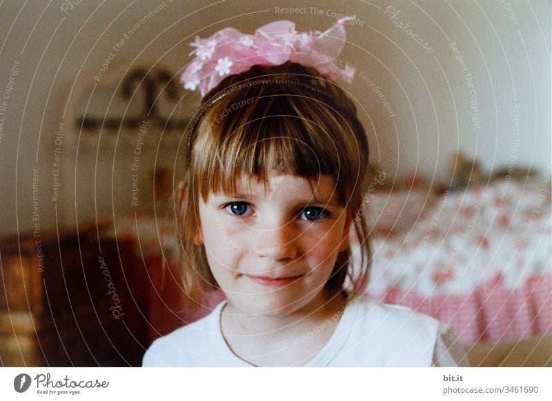 Little girl is blissfully happy with her hair ornament of pink flowers and is dressed as a princess with a crown of flowers. Girlish Portrait of a young girl