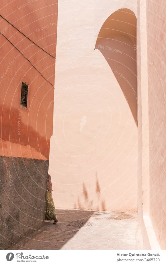 Moroccan girl crossing a corner Marrakech Morocco adobe africa architecture art building city edge empty family handkerchief house intersection medina no person