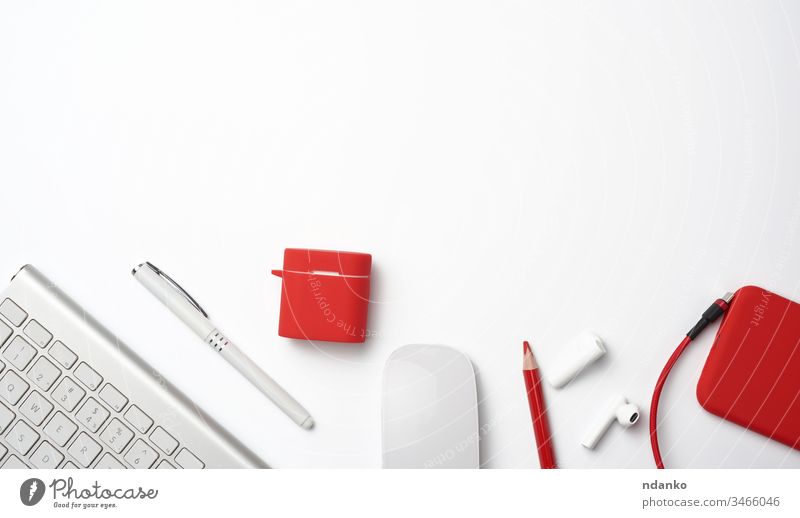 White wireless keyboard, red smartphone, mouse on a white background above blank business computer design designer desk desktop device document earphone