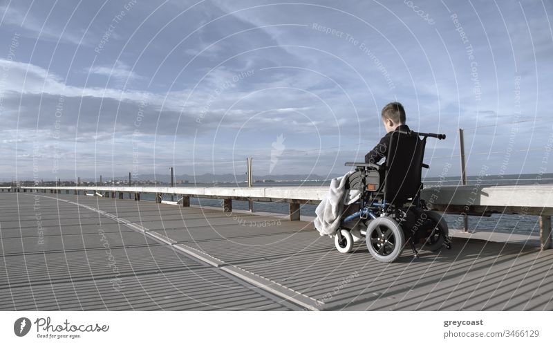 Handicapped child is lonely in this big active world. Disabled boy in wheelchair outdoor alone, shot in grey tints handicap disabled depression kid handicapped