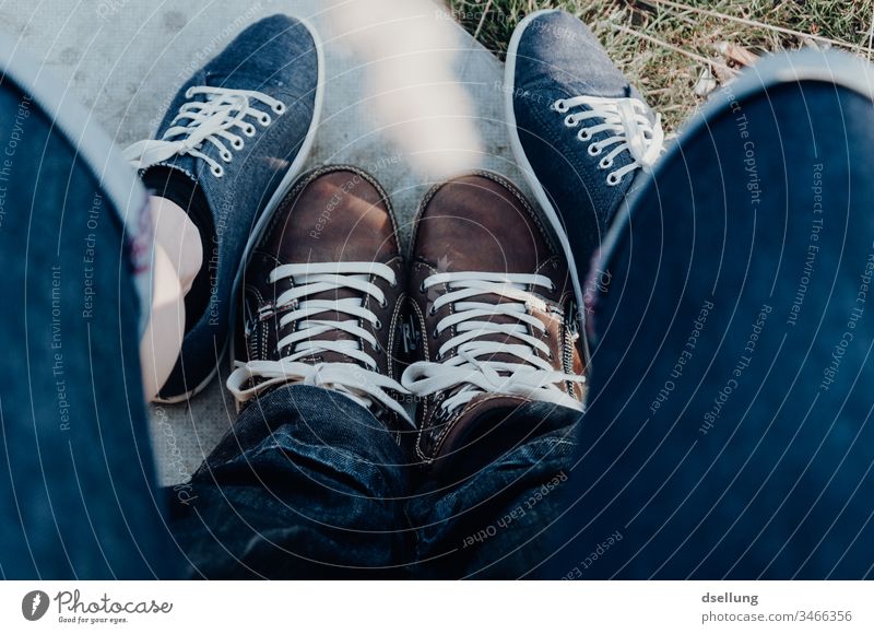 Young couple shows their feet relaxed in modern shoes and form an inspiring formation Bird's-eye view Deep depth of field Sunlight Shadow Light Day Deserted