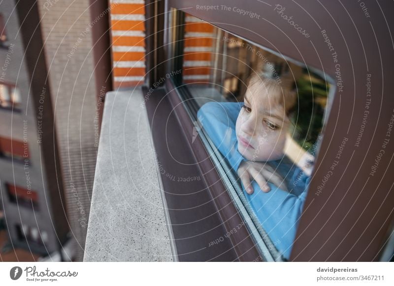 Sad girl looking out the window sad through the glass melancholic coronavirus confinement covid-19 boring sadness looking through the window quarantine