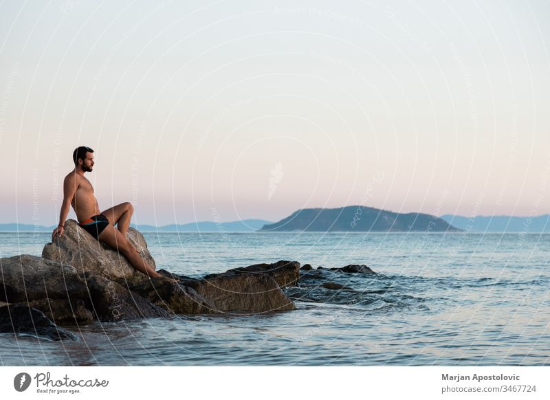 Young man enjoying sunset on the beach adult adventure alone beautiful calm coast dawn dusk evening freedom harmony holiday horizon island landscape lifestyle