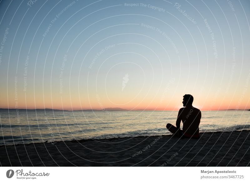 Young man enjoying sunset on the beach adult adventure alone beautiful calm coast dawn dusk evening freedom harmony holiday horizon island landscape lifestyle